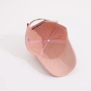 Detailed interior of a pink cotton baseball cap with stitch lines and adjustable metal buckle