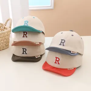 Detailed pile of colorful soft brim baby baseball caps with R embroidery and cotton fabric