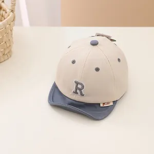 Detail of baby cotton baseball cap with embroidered letter R and soft contrast brim