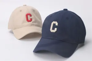 Detailopname van katoenen baseballpetten met geborduurde C-letter in beige en marineblauw