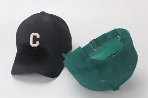 Detail van de verstelbare metalen gesp en het geborduurde letter C op de katoenen petten