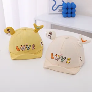 Detalle de gorras de bebé amarillo y crema con bordado LOVE y orejas decorativas