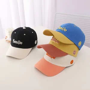Detail of four colorful kids' baseball caps with 'Smile' 3D embroidery and side smile patches