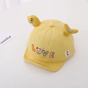 Detalle de gorra de béisbol amarilla para bebé con aletas de dibujos y bordado LOVE tela