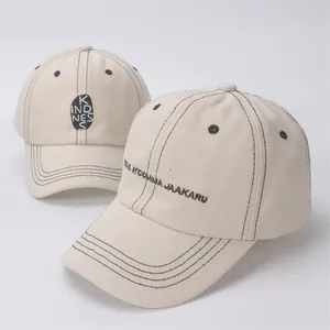 Detail of beige cotton baseball caps featuring contrast black stitching and embroidery