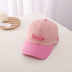 Close-up of pink Smile embroidery on kids' baseball cap with contrasting two-tone panels