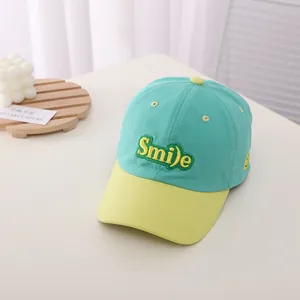 Detailed embroidery of Smile letters on a mint green and yellow cotton baseball cap