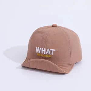 Detail of caramel baby baseball cap with white WHAT ON HOLIDAY embroidery and soft brim