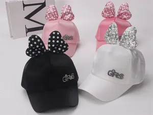 Détails des nœuds à pois pailletés et logos en strass sur des casquettes en satin