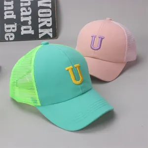 Close-up of mesh trucker hats in mint green and pink with letter U embroidery