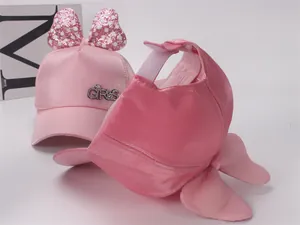 Vue détaillée de la casquette rose avec nœud pailleté et décoration en strass
