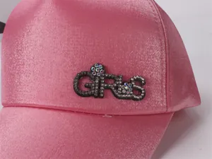 Gros plan d'une casquette en satin rose pour filles avec lettrage GIRLS en strass