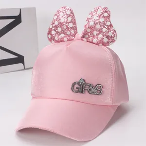 Détail d'une casquette rose pour fille avec nœud à paillettes et lettrage GIRLS en strass