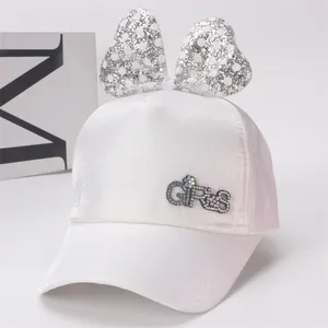 Détail de la casquette en satin blanc pour filles avec gros nœud argenté et logo en strass