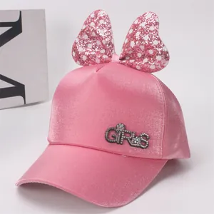 Détail d'une casquette rose pour fille avec nœud à paillettes et motif GIRLS en strass