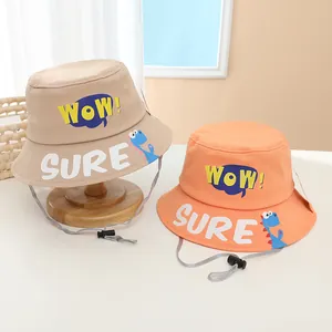 Detail of kids beige and orange bucket hats with WOW letters and dinosaur patterns