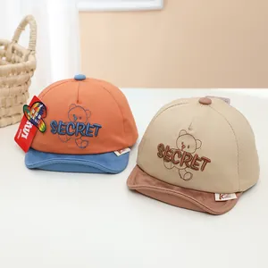 Détail de deux casquettes pour bébés avec broderie d'ours et visières souples