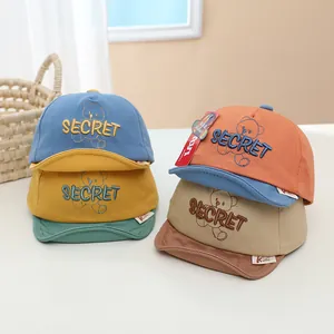Gros plan détaillé de casquettes en coton coloré avec broderie Secret et motif ours