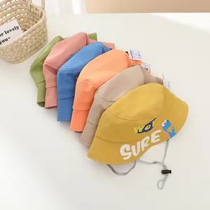 Pile of colorful kids canvas bucket hats with cartoon dinosaur and windproof strings