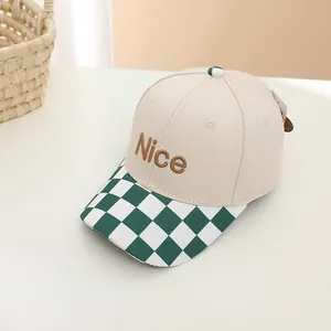 Detail view of beige baseball cap with checkered brim and Nice embroidery for kids