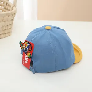 Détail de casquette enfant bleu ciel avec visière jaune et étiquette de marque