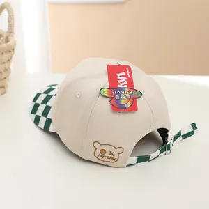Detail of kids baseball cap featuring beige fabric, bear embroidery and checkerboard strap