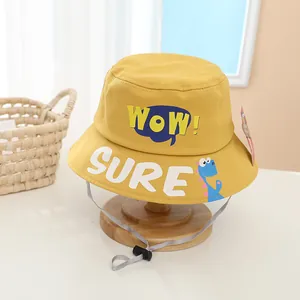Detail of yellow kids bucket hat with SURE and WOW text and small blue dinosaur print