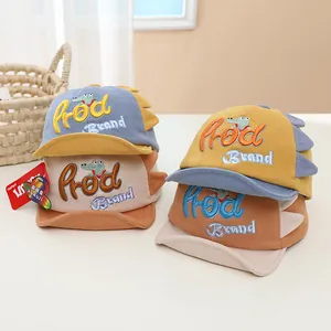 Close-up of cute dinosaur baby baseball caps featuring colorful embroidery and 3D dinosaur fins