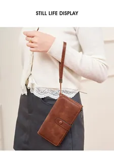 Portefeuille long en cuir marron vintage avec dragonne tenu par un mannequin en scène