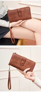 Gros plan d'un long portefeuille vintage en cuir marron avec dragonne et double fermeture