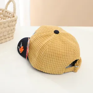 Detail view of corduroy baseball cap with metal buckle and orange letter embroidery