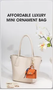 Detailed view of orange leather mini bag charm with floral scarf on a cream tote bag
