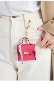 Rose pink mini leather bag charm with silk scarf detail hanging on white jeans