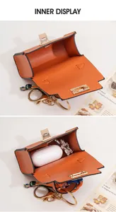 Internal view of orange mini bag charm showing storage for wireless earbuds and accessories