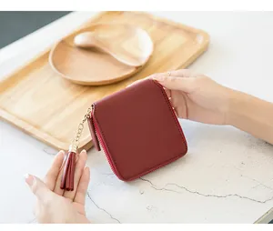 Close-up of burgundy square zip wallet with leather tassel and fine textured grain finish