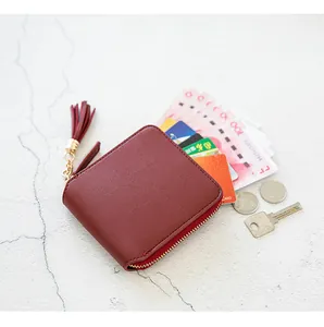 Close-up of burgundy zip-around wallet with golden zipper and stylish tassel detail