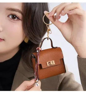 Detailed view of mini brown leather keychain bag for AirPods with silk scarf accent