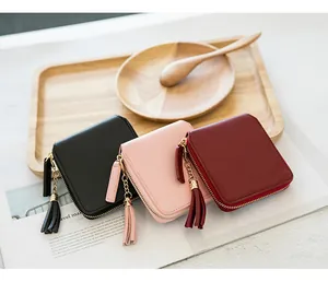 Detailed view of square zip wallets in black, pink, and burgundy with tassel charms