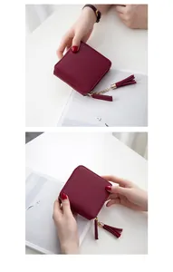 Detail of burgundy square mini wallet featuring gold zippers and twin tassel charms