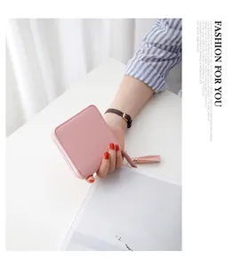 Macro shot of a pink pebbled leather mini wallet featuring a stylish gold tassel zipper