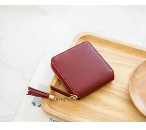 Detail of burgundy leather square wallet with gold zipper and stylish tassel pendant