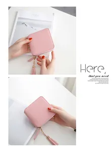 Close-up of pink square wallet with silver zipper and decorative tassel detail