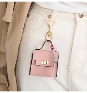 Mini pink litchi leather bag charm with silk scarf detail hanging on white denim jeans