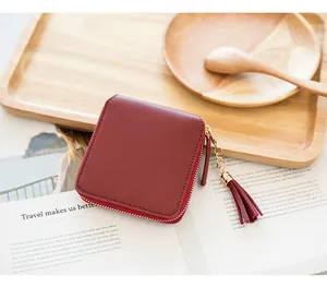 Close-up of burgundy square zip wallet with leather tassel on a book background