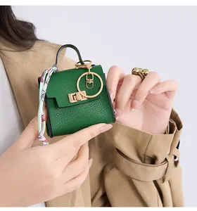 Close-up of green lychee leather mini bag charm with silk scarf handle and gold buckle