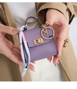 Mini purple leather keychain bag with golden twist lock and decorative floral silk scarf