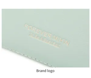 Macro detail of mint green litchi leather with gold embossed logo and fine stitching