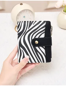 Close-up of zebra pattern RFID wallet held by hand showing compact size and texture