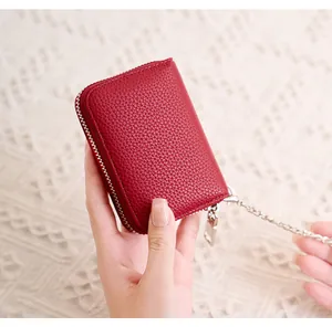 Detail of red lychee grain leather card holder with silver zipper and metal chain link