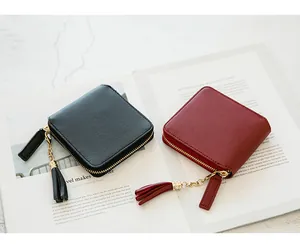 Close-up of square leather wallets with pebble texture and tassel zippers in black and red